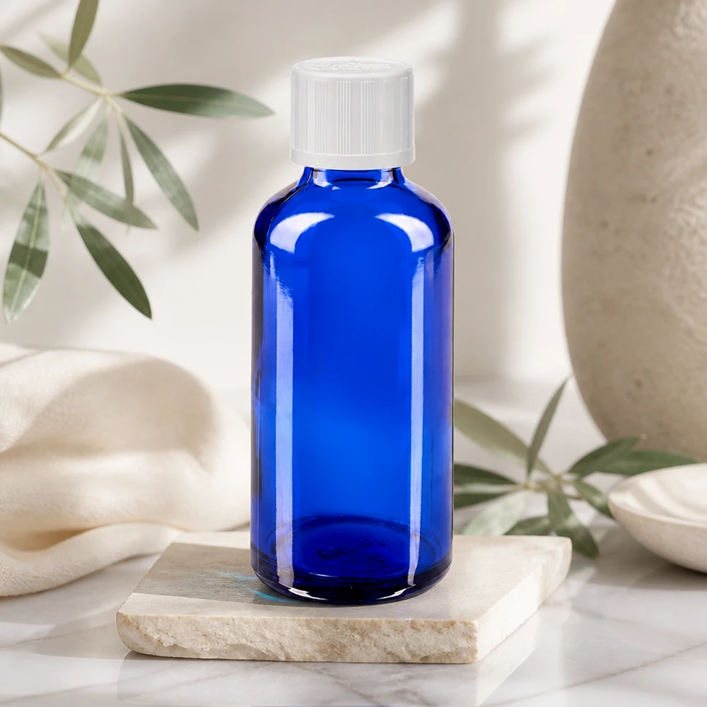 Frasco de farmácia azul 50ml tampa conta-gotas branco padrão resistente a crianças Garrafa de vidro azul de 50 ml com tampa de rosca branca sobre uma pedra de mármore num ambiente natural e luminoso